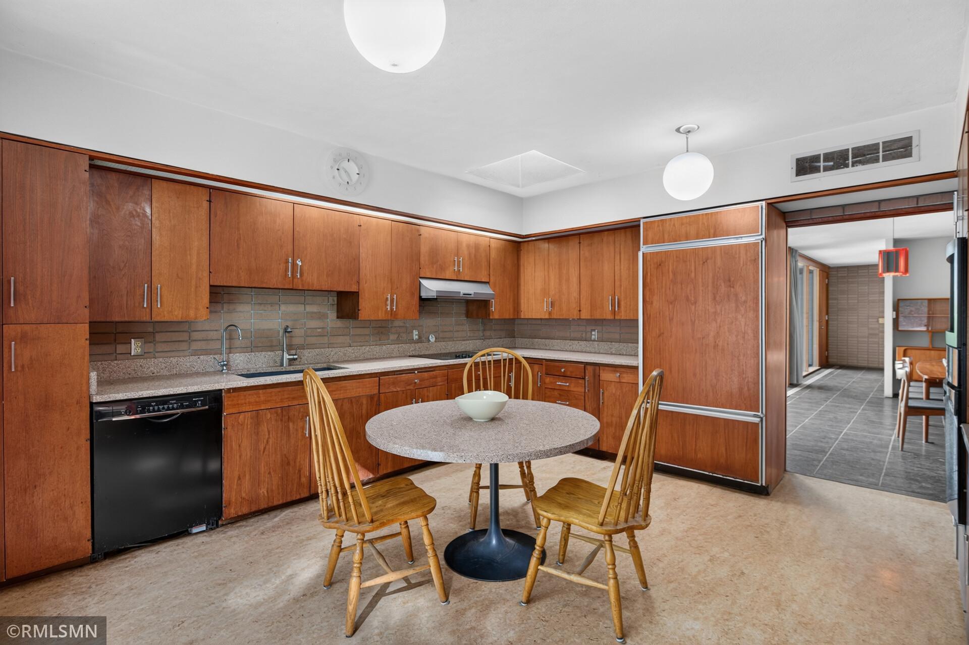 Kitchen with extensive wood cabinetry, tiled backsplash, and a round dining table with wooden chairs.
