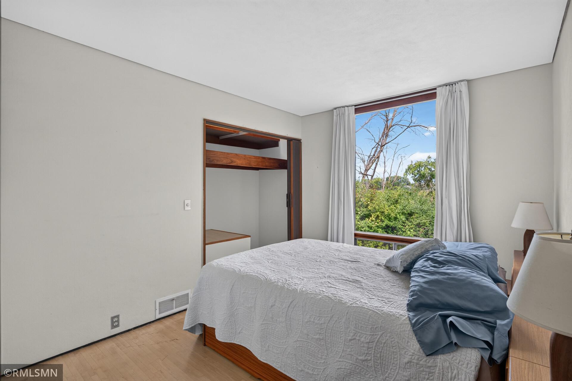 Bedroom with white and blue bedding, a curtained window, and a built-in sleeping alcove.