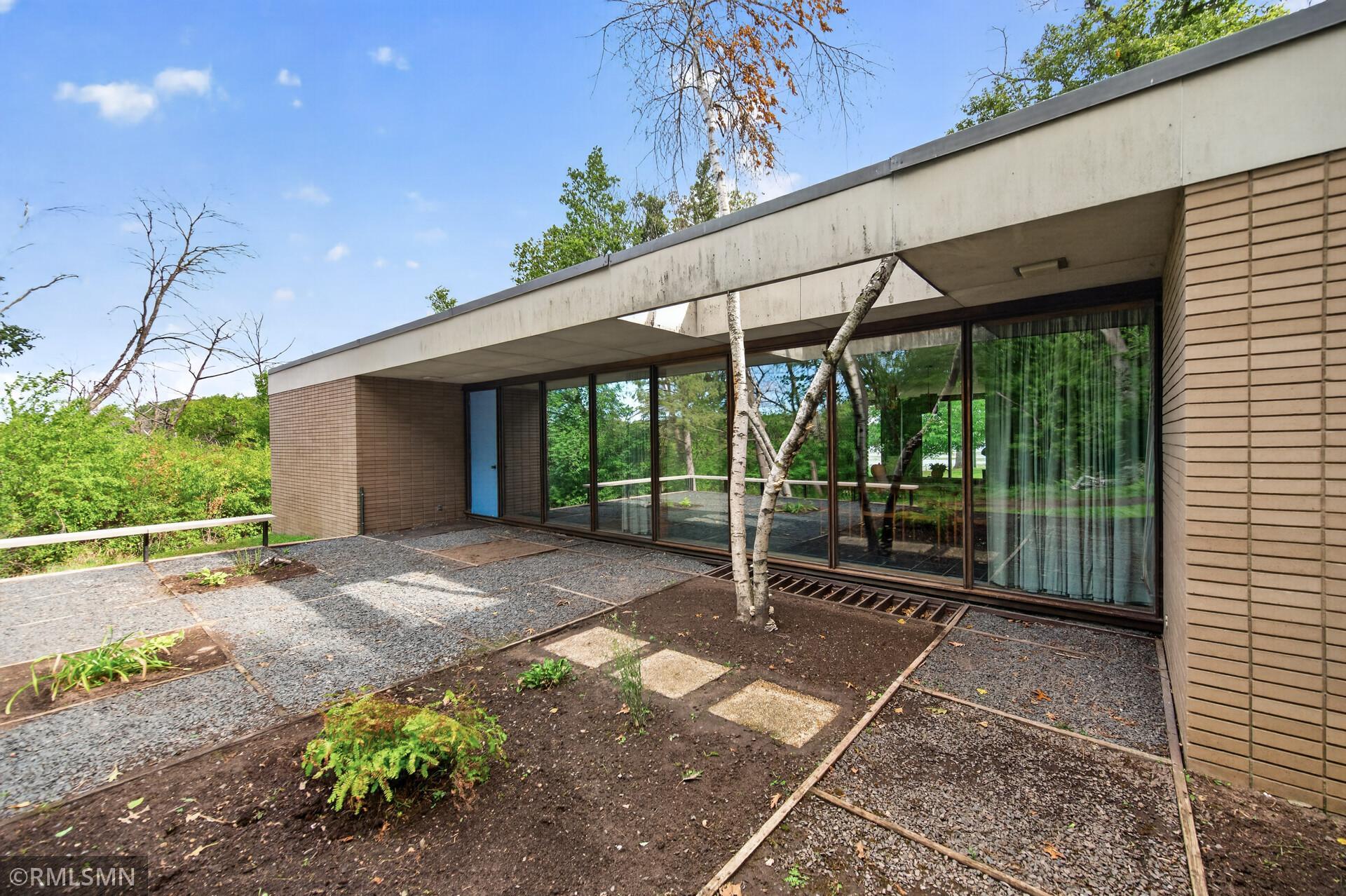 Modern brick home with a flat roof, broad glass doors, and a gravel patio.