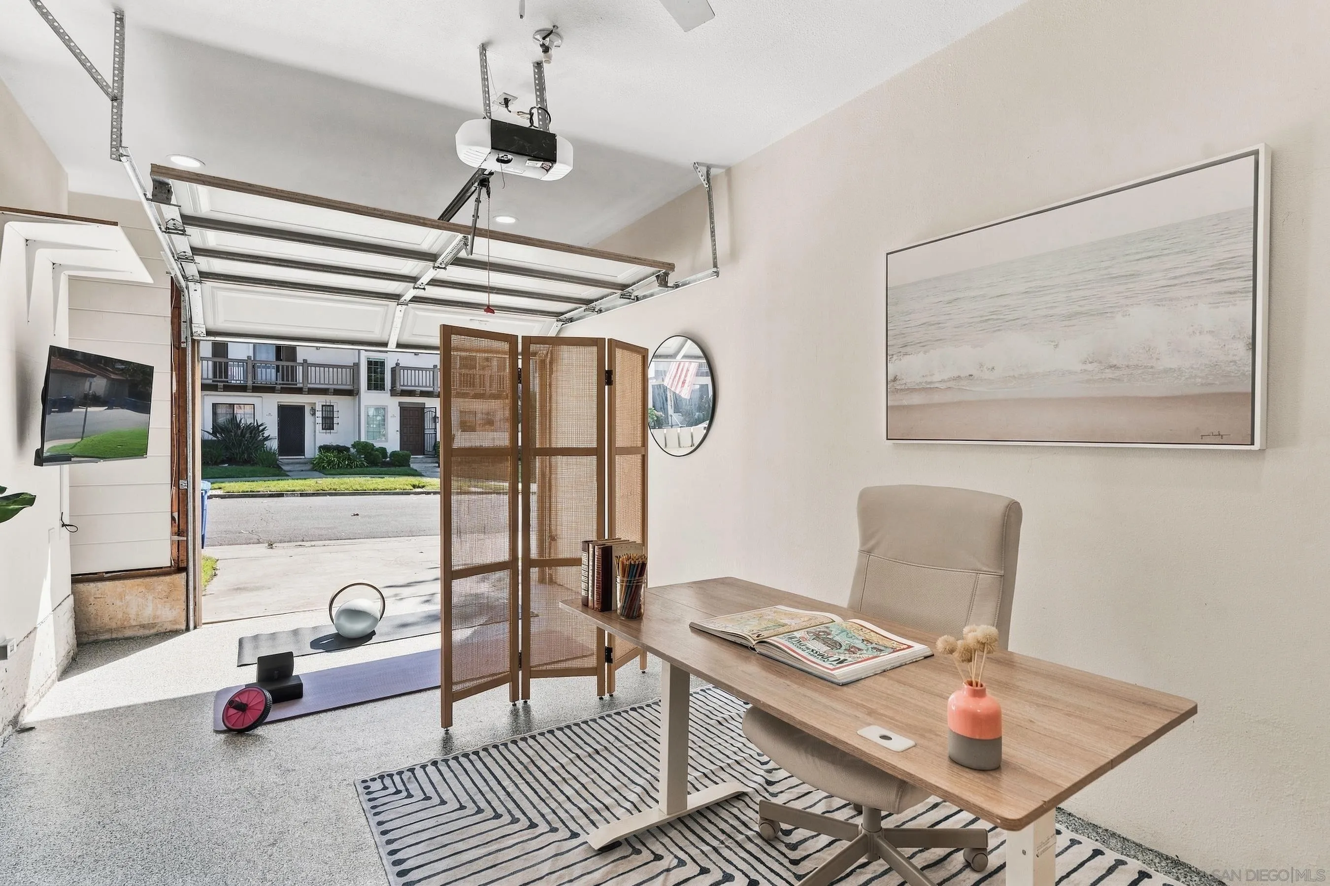 Staged garage office with a wooden desk, folding screen, and open garage door.