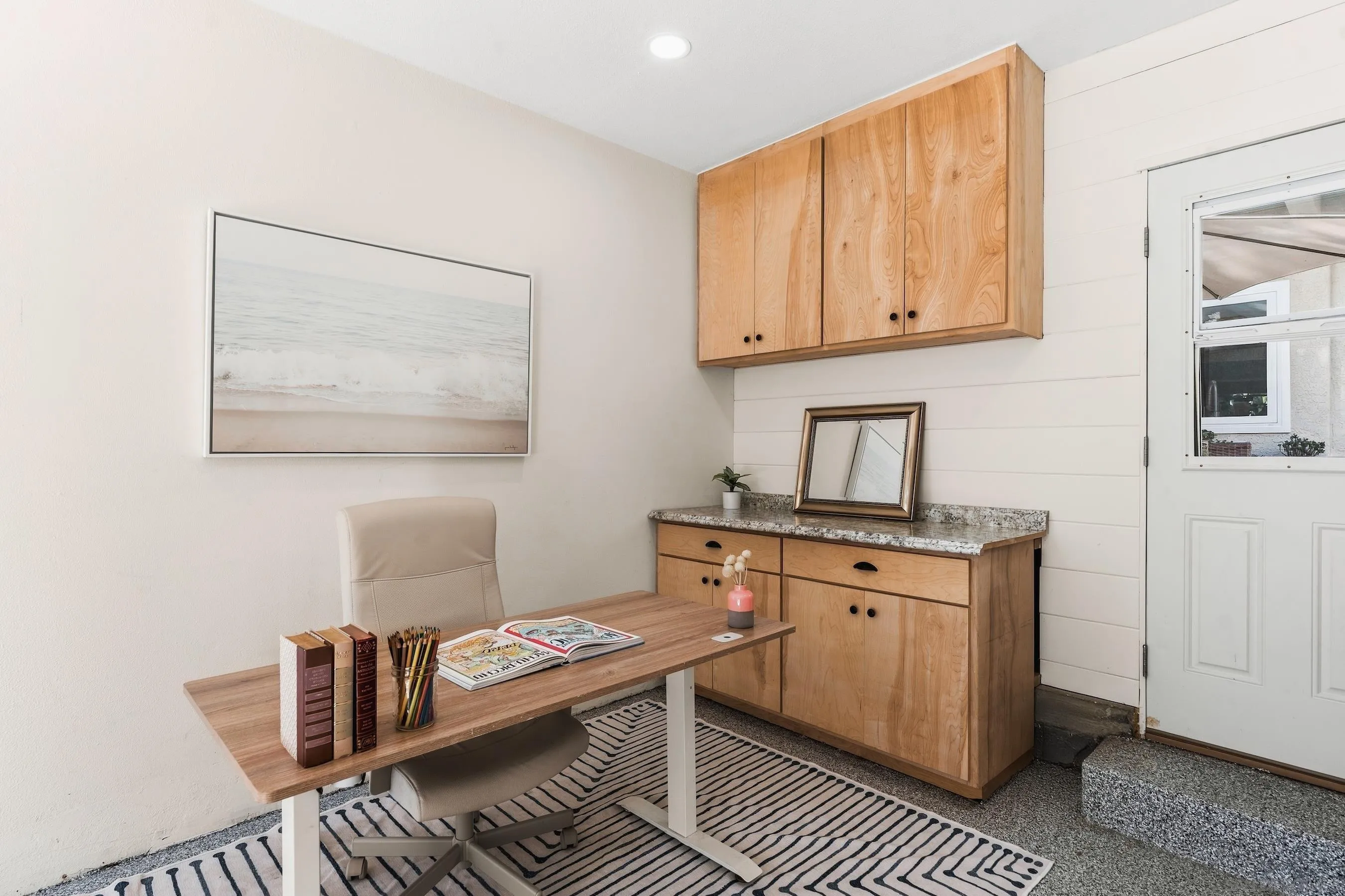 Home office with a wood desk and matching cabinetry beside a white entry door.