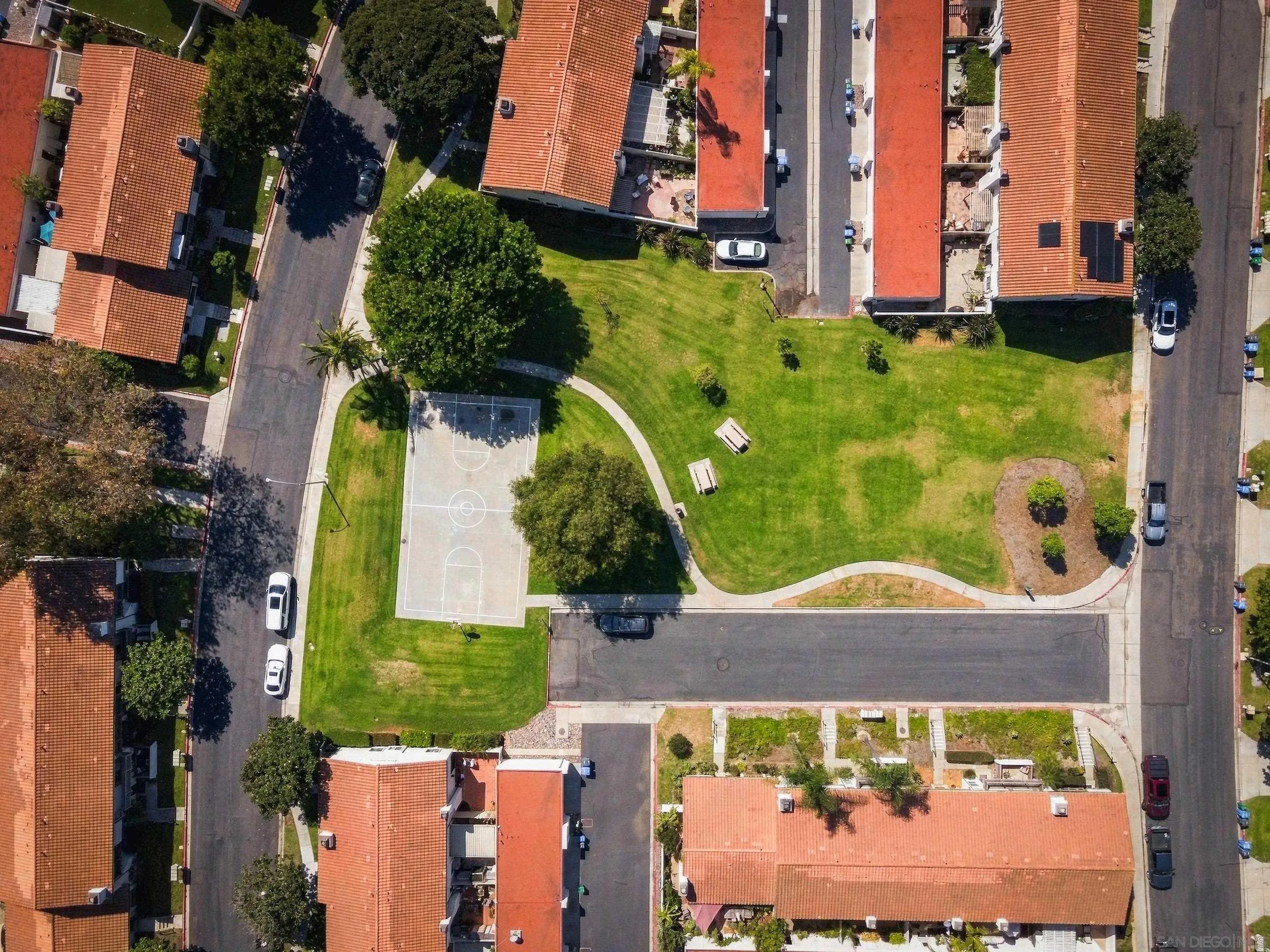 Aerial view of homes around a shared courtyard with a basketball court and curving paths.