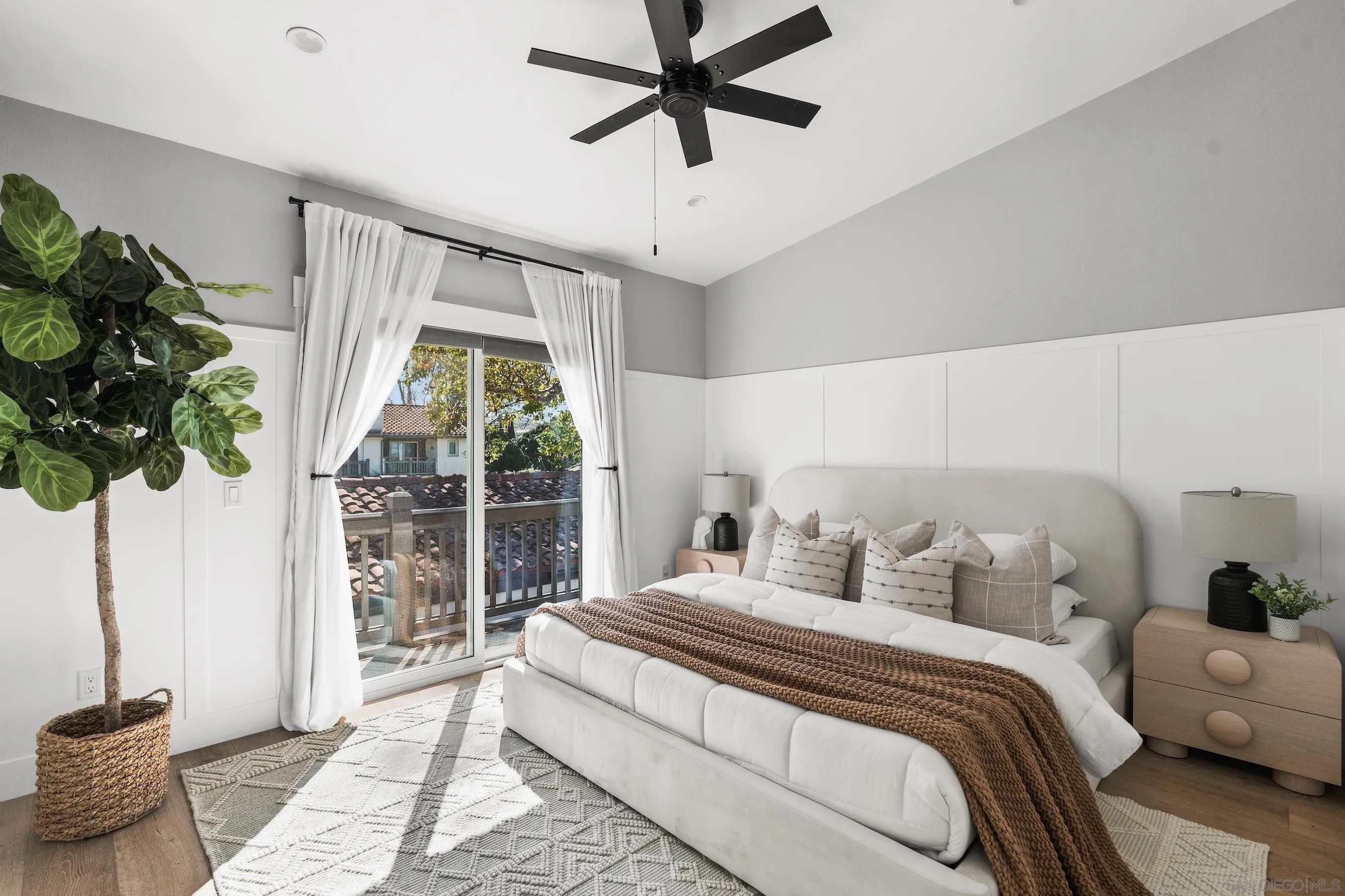 Bedroom with a white bed, black ceiling fan, and sliding glass door to a balcony.