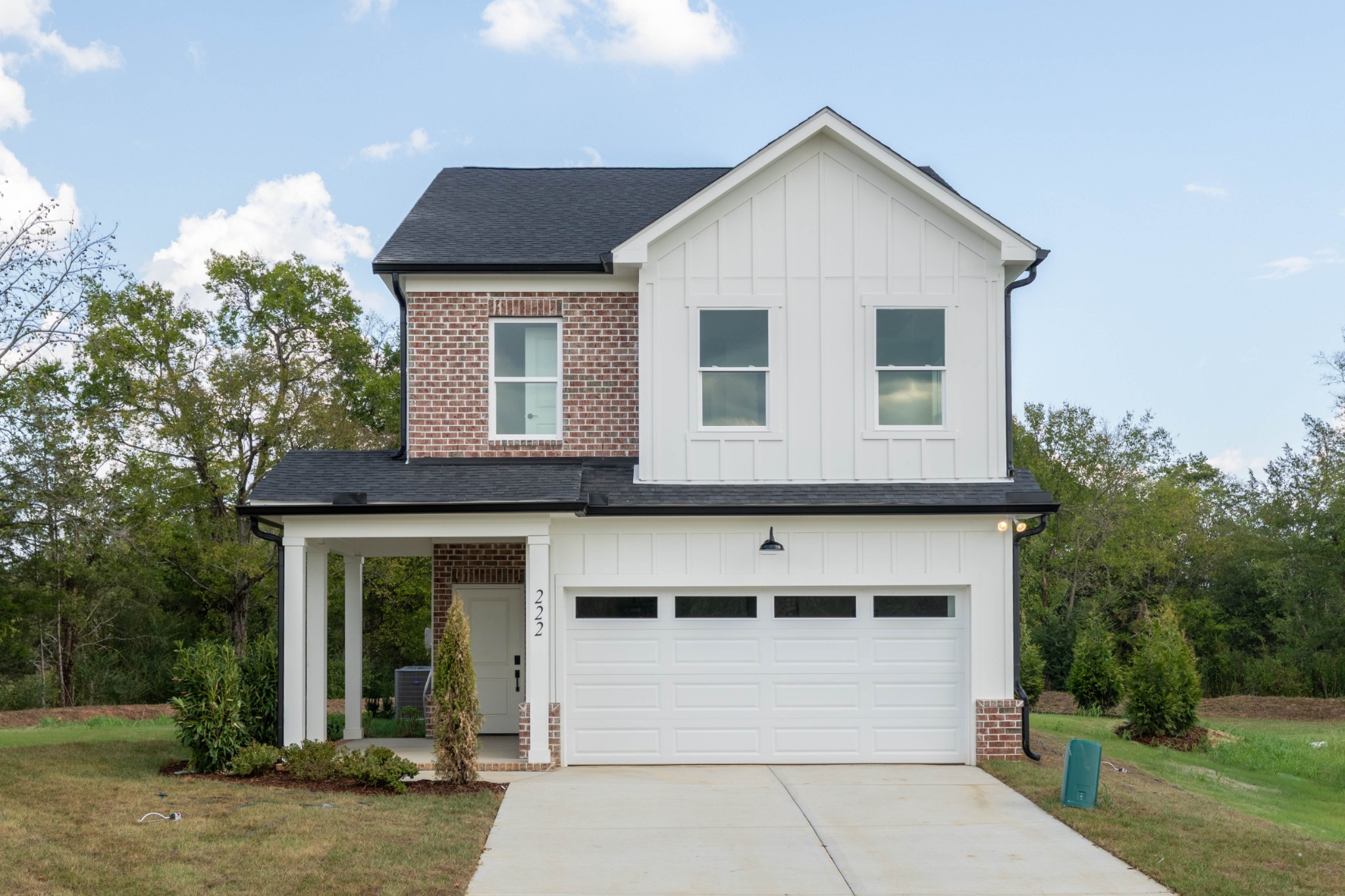 Two-story white-and-brick house with a covered porch and attached garage.