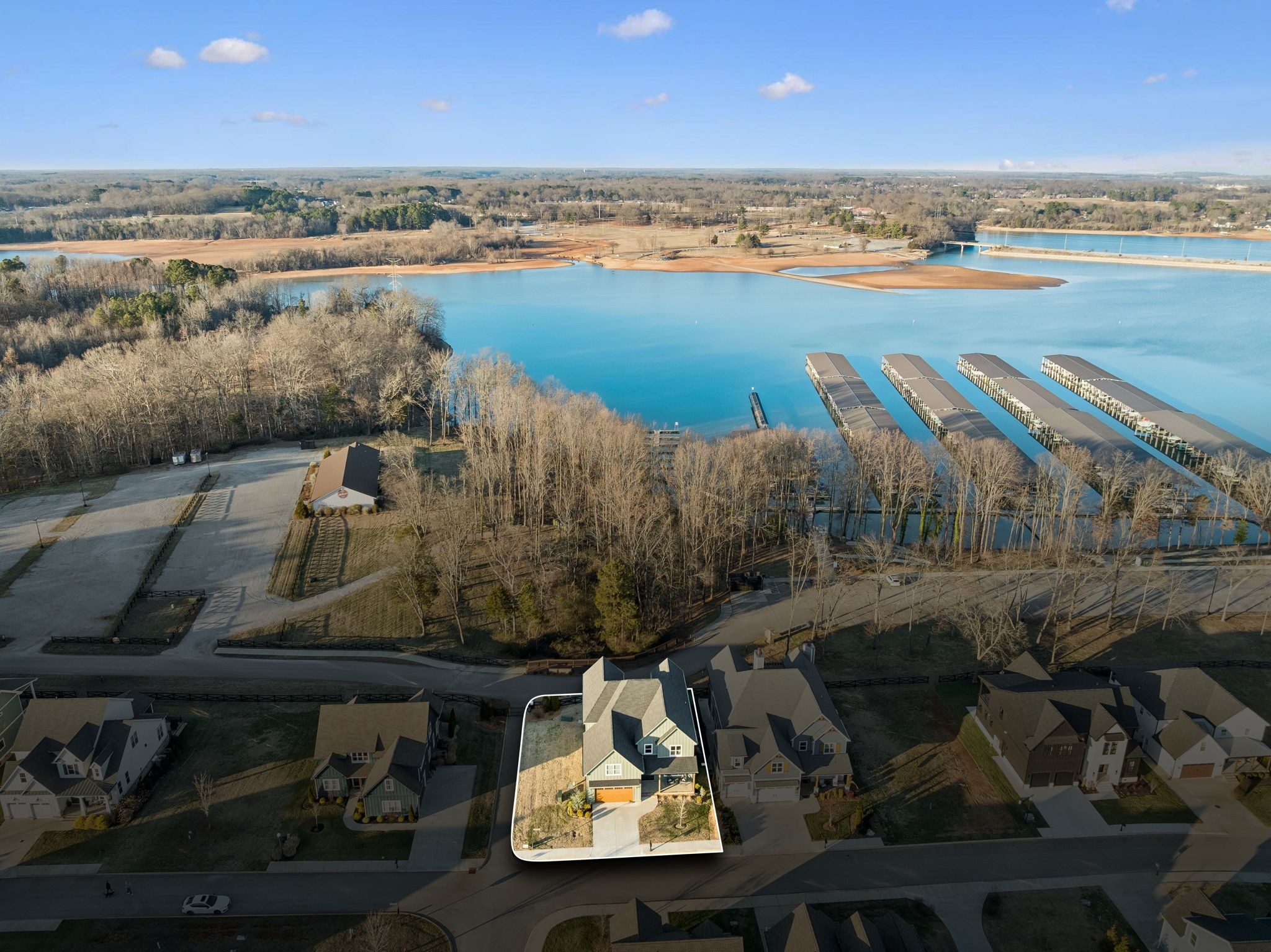 Aerial view of a highlighted two-story home beside a lake with marina docks.