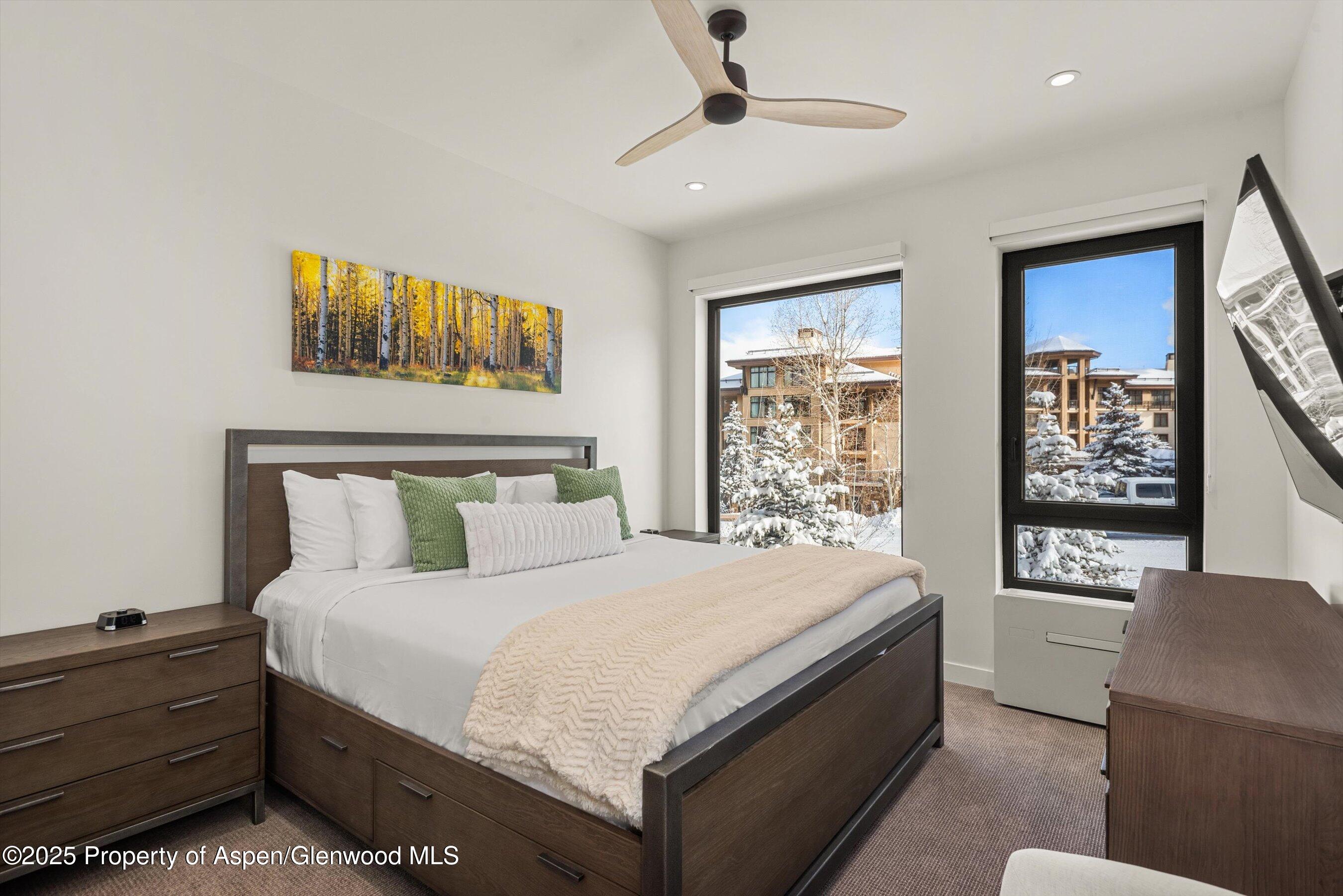 Bedroom with dark wood furnishings and snow-covered trees visible through the windows.