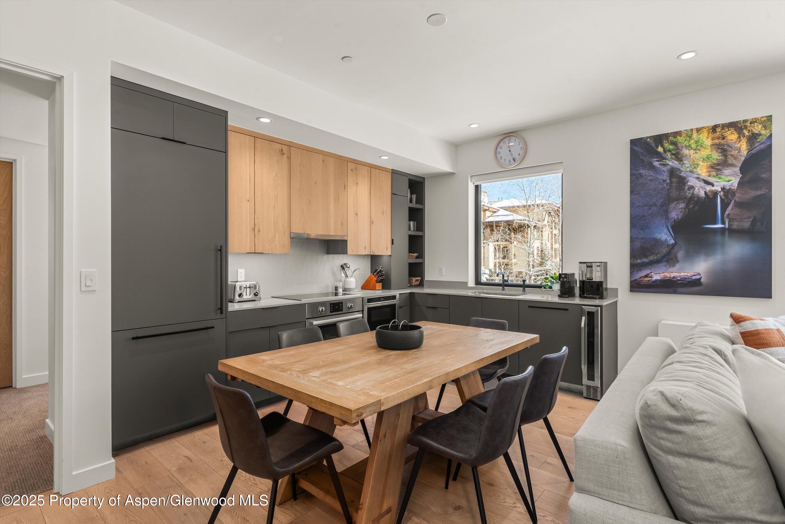 Open kitchen and dining area with charcoal cabinets, a wood table, and a gray sofa.