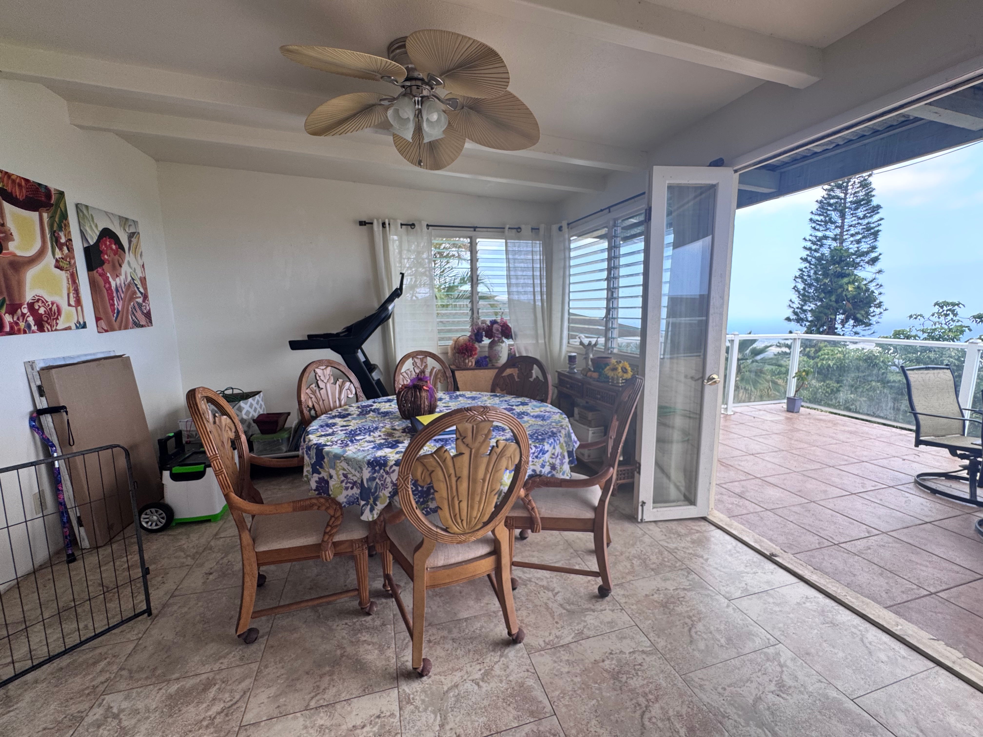 Dining area with carved wooden chairs and round table opening onto an ocean-view lanai.
