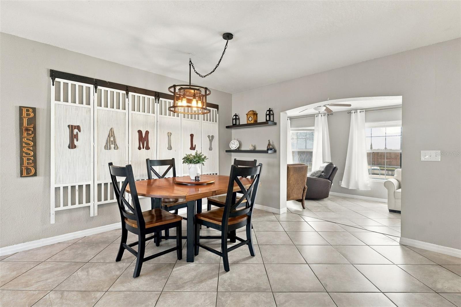 Dining room with a round wooden table, dark chairs, and a white decorative screen.