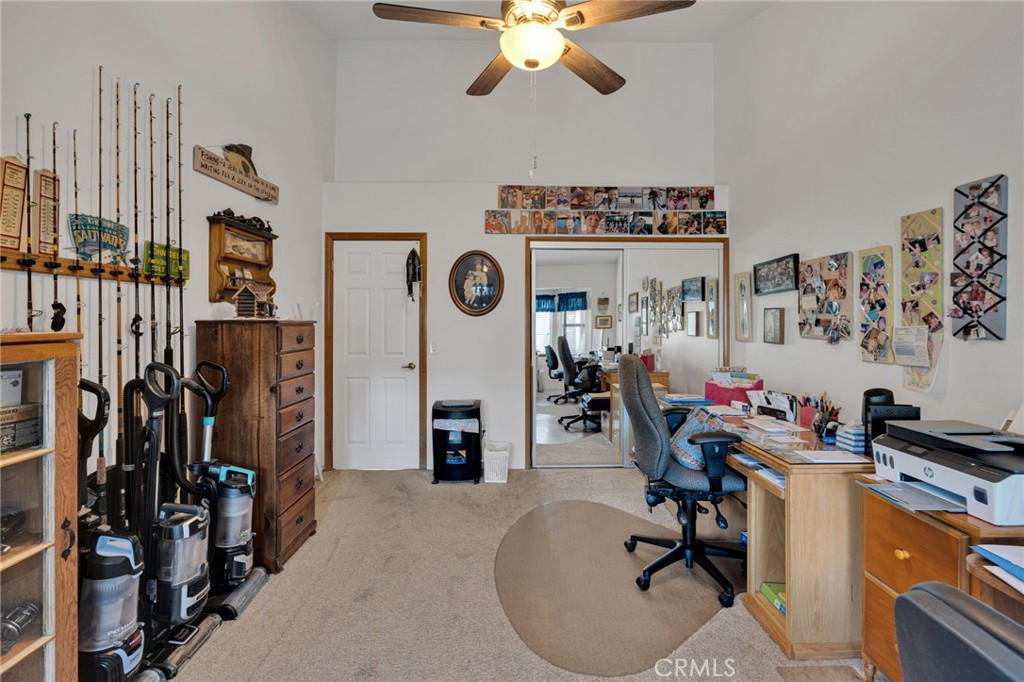 Home office with desks and computers, fishing rods displayed along one wall, and vacuum cleaners gathered by a dresser.
