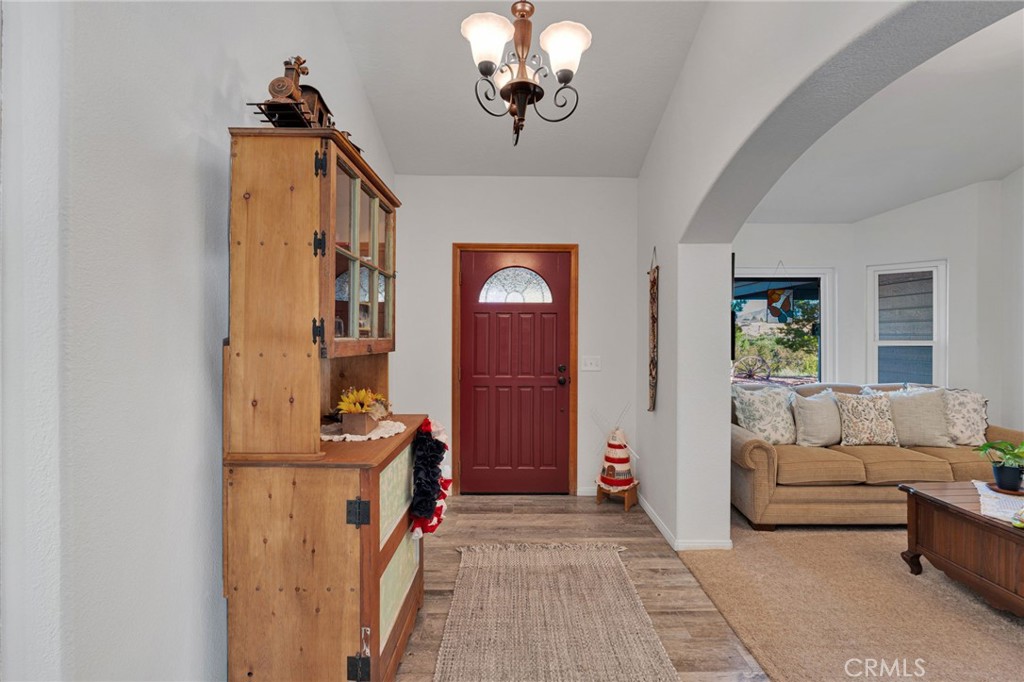 Home entryway with a red front door, wooden hutch, and arched opening to the living room.