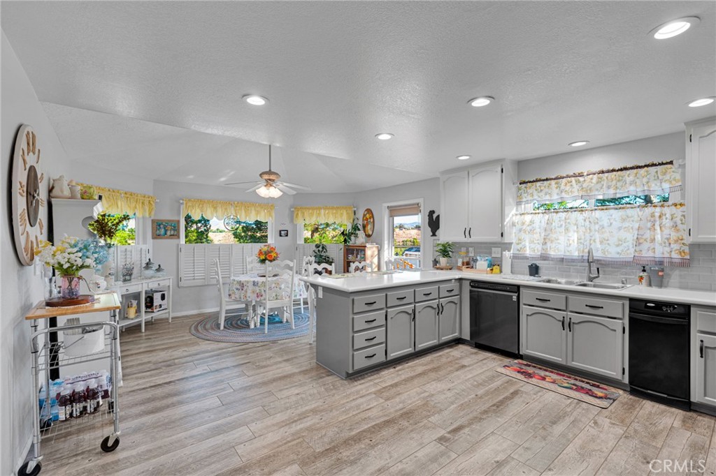 Kitchen with gray cabinets and central island opening onto a dining area with windows.