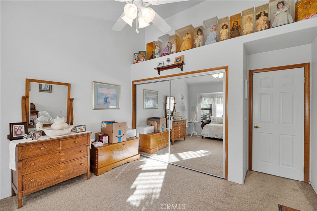 Bedroom with mirrored closet doors, wooden dressers, and dolls displayed along a high shelf.