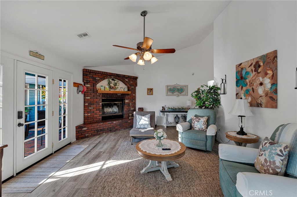 Living room with a brick fireplace, teal seating, and glass doors opening to a patio.