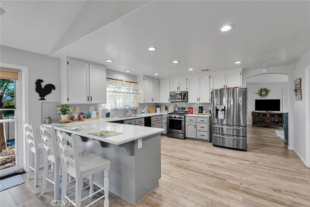 Open kitchen with a large white island, bar stools, and stainless steel appliances.