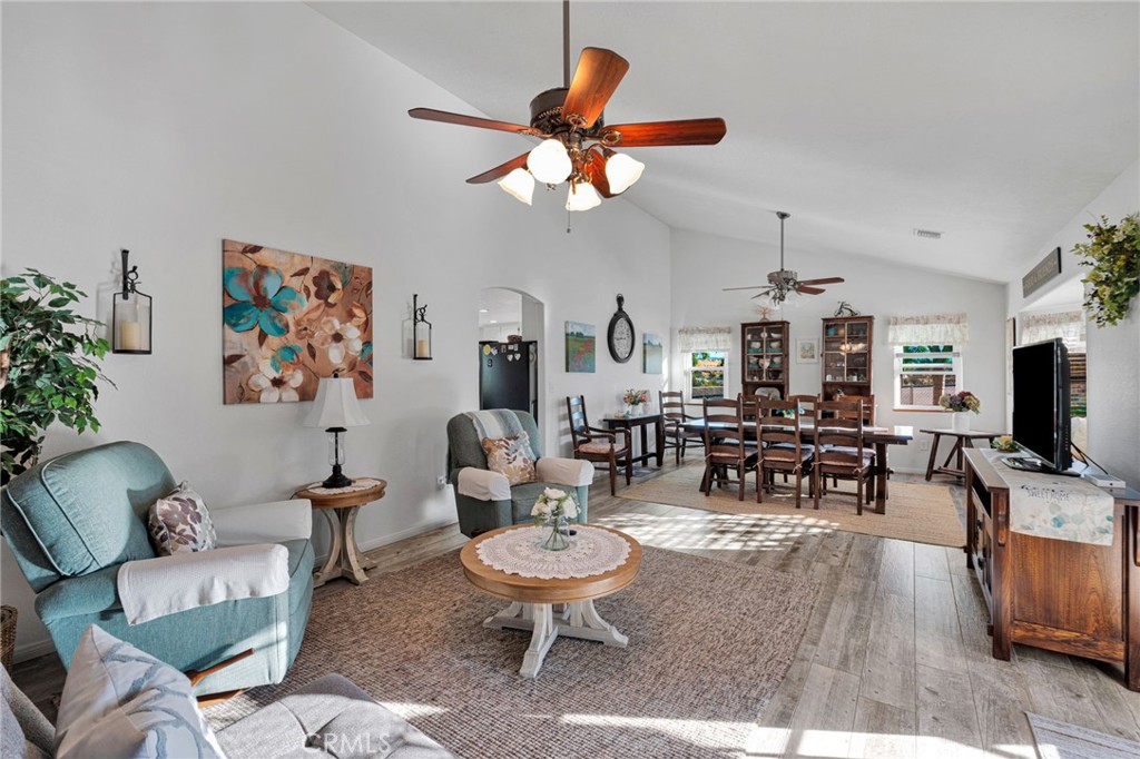 Open-plan living and dining room with teal seating, wood floors, and ceiling fans.