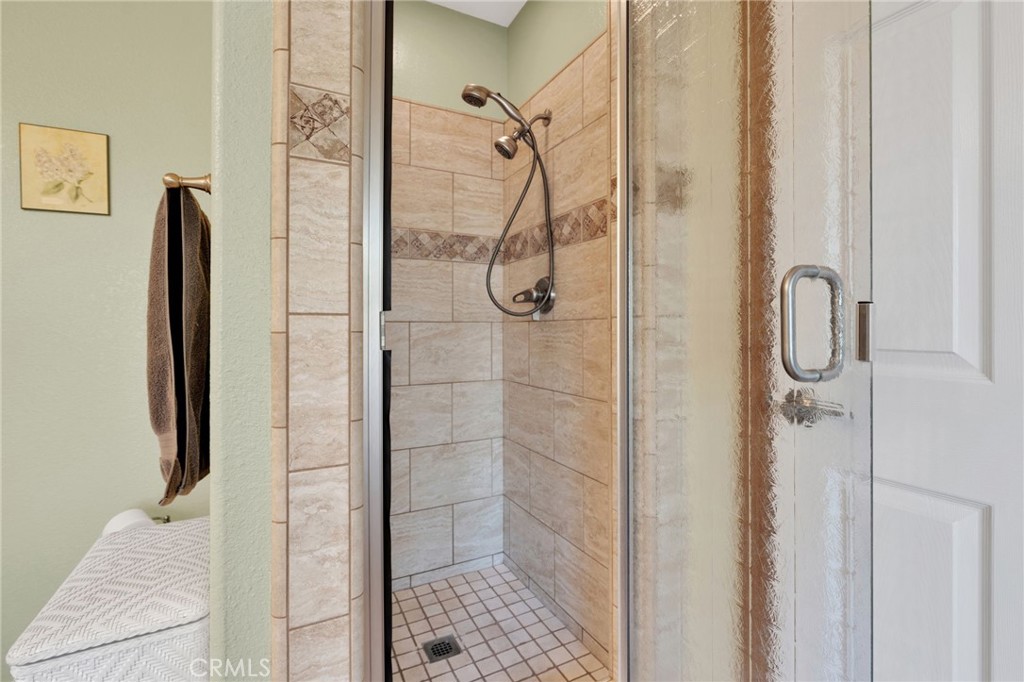 Tiled walk-in shower with a glass door and handheld showerhead.