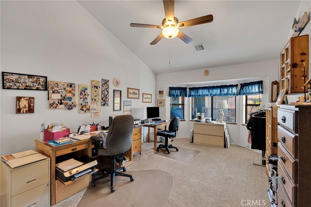 Home office with two workstations, a carpeted floor, and a wide bay window with blue curtains.