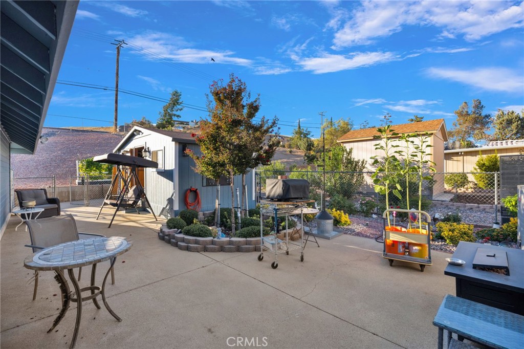 Fenced backyard patio with outdoor seating, a swing, and garden beds.