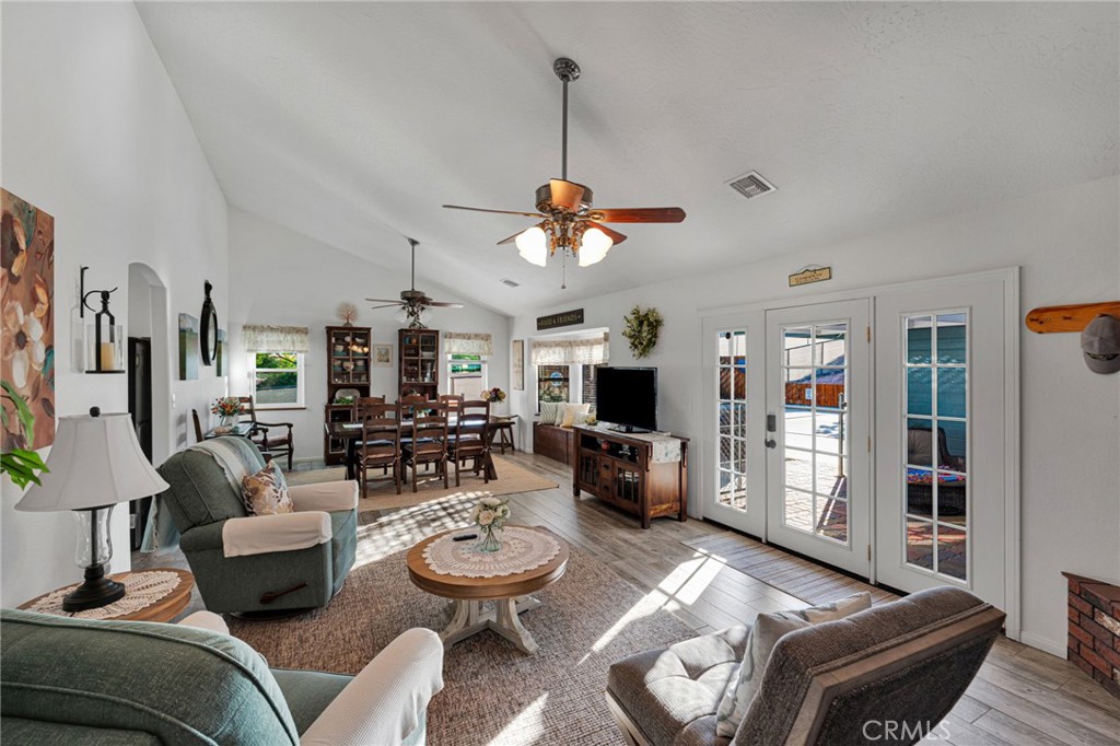 Open-plan living and dining room with glass doors to a patio and ceiling fans.