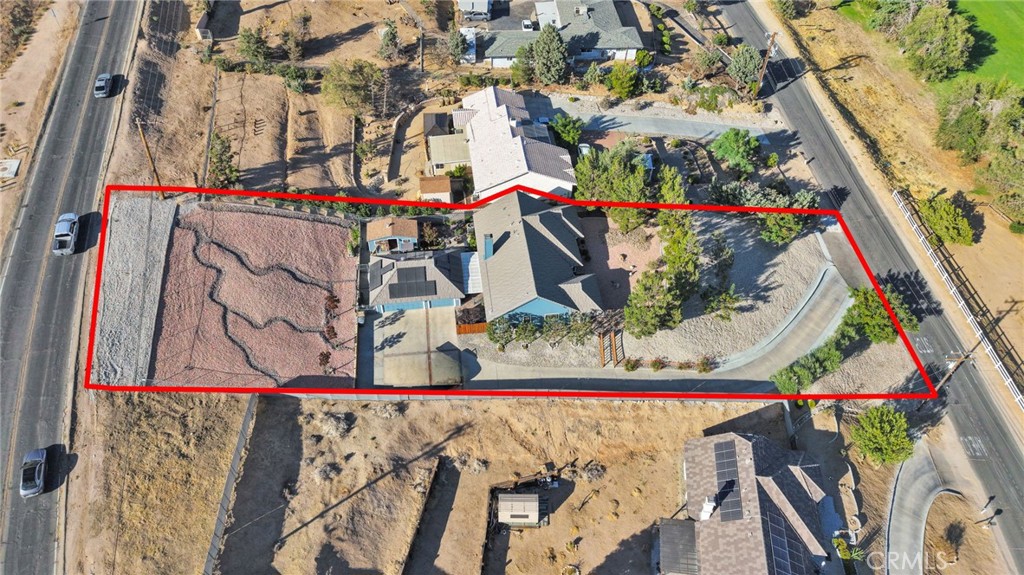 Aerial view of a house and lot outlined in red, with roads along both sides.