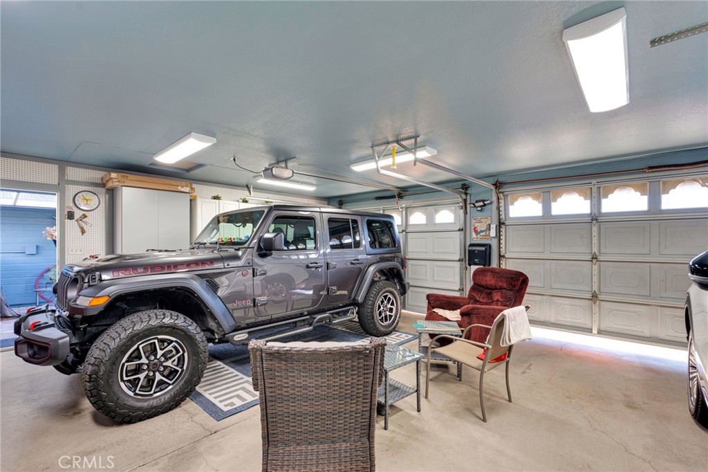 Garage with a gray Jeep, two garage doors, and a small seating area.