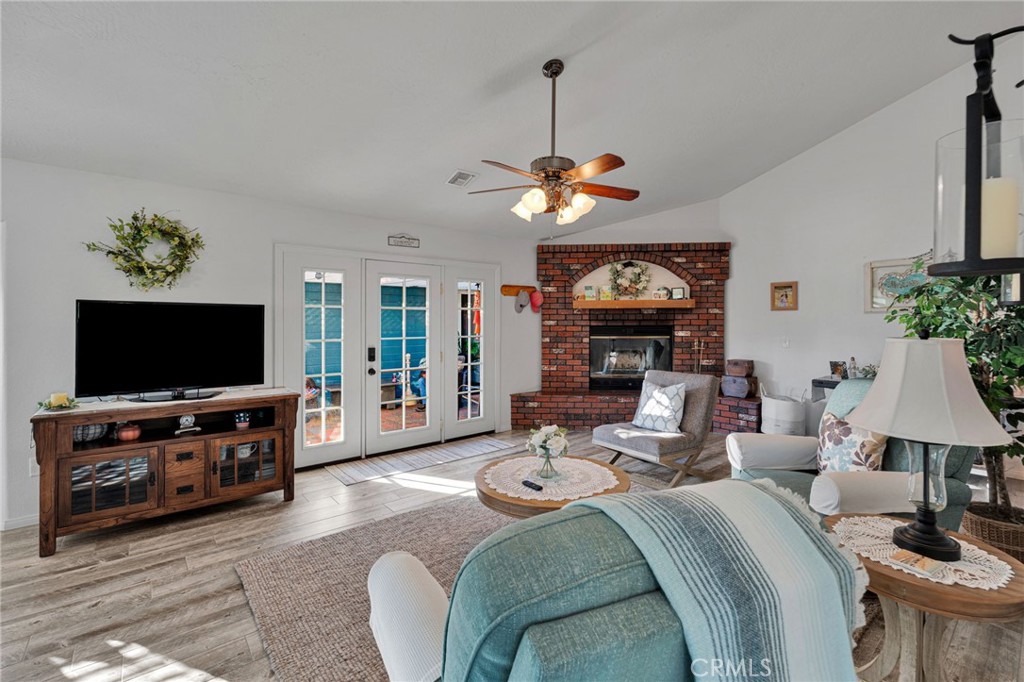 Furnished living room with a brick fireplace, French doors, and a ceiling fan.