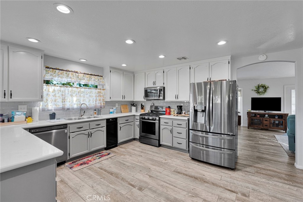 Kitchen with white cabinetry, stainless steel appliances, and an open connection to the living area.