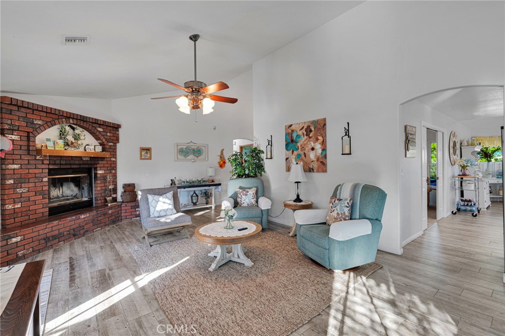Living room with a red brick fireplace, teal armchairs, and a ceiling fan.