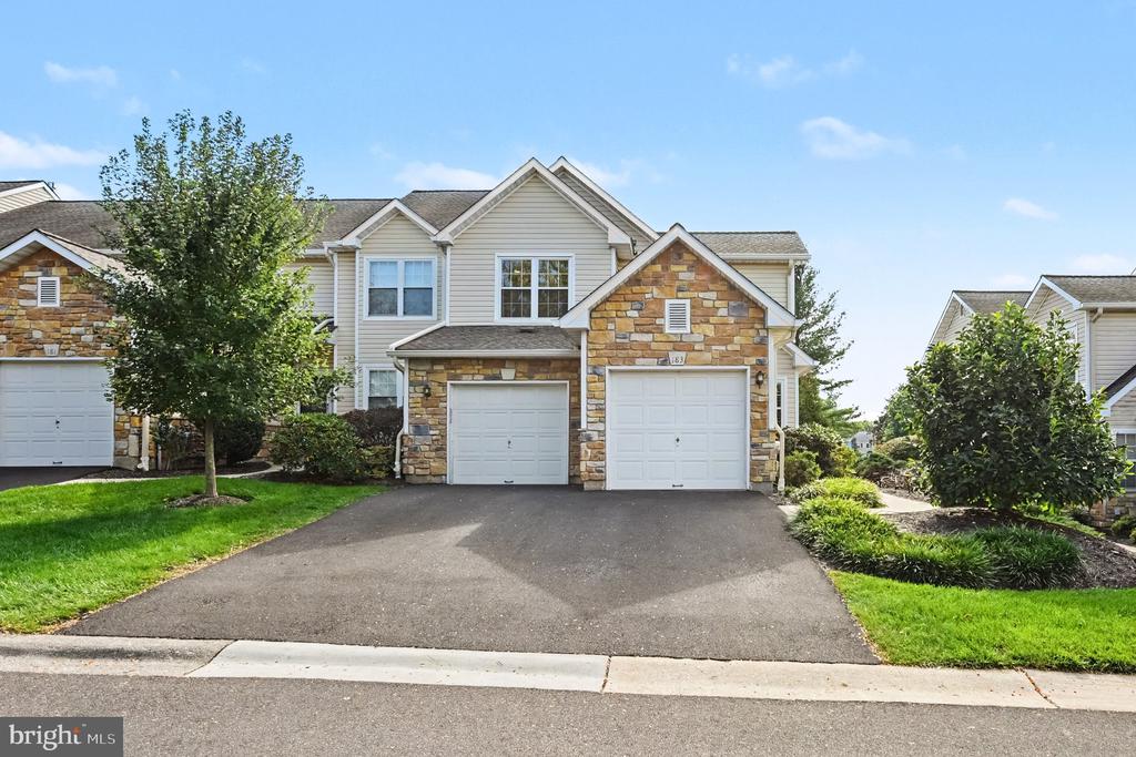Two-story attached home with stone accents, two garage doors, and a wide driveway.
