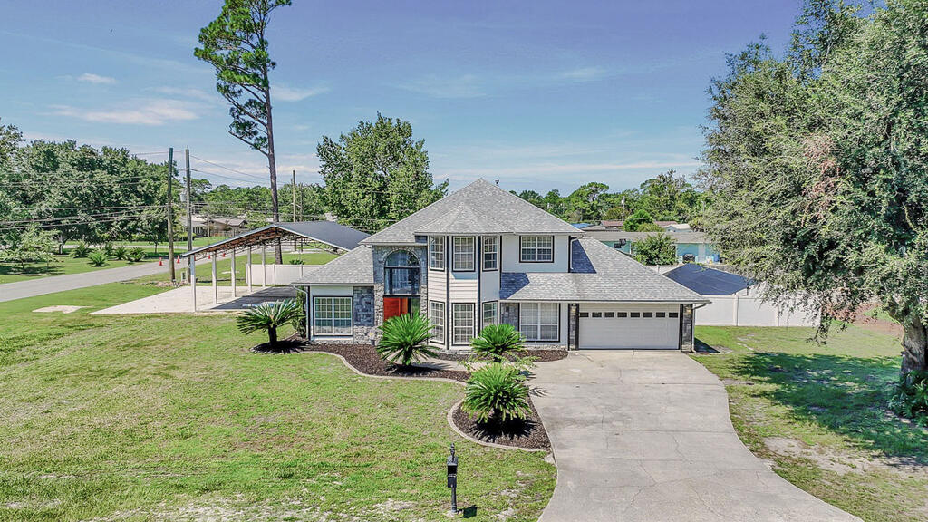 Two-story house with stone accents, an attached garage, and a metal-roofed carport.
