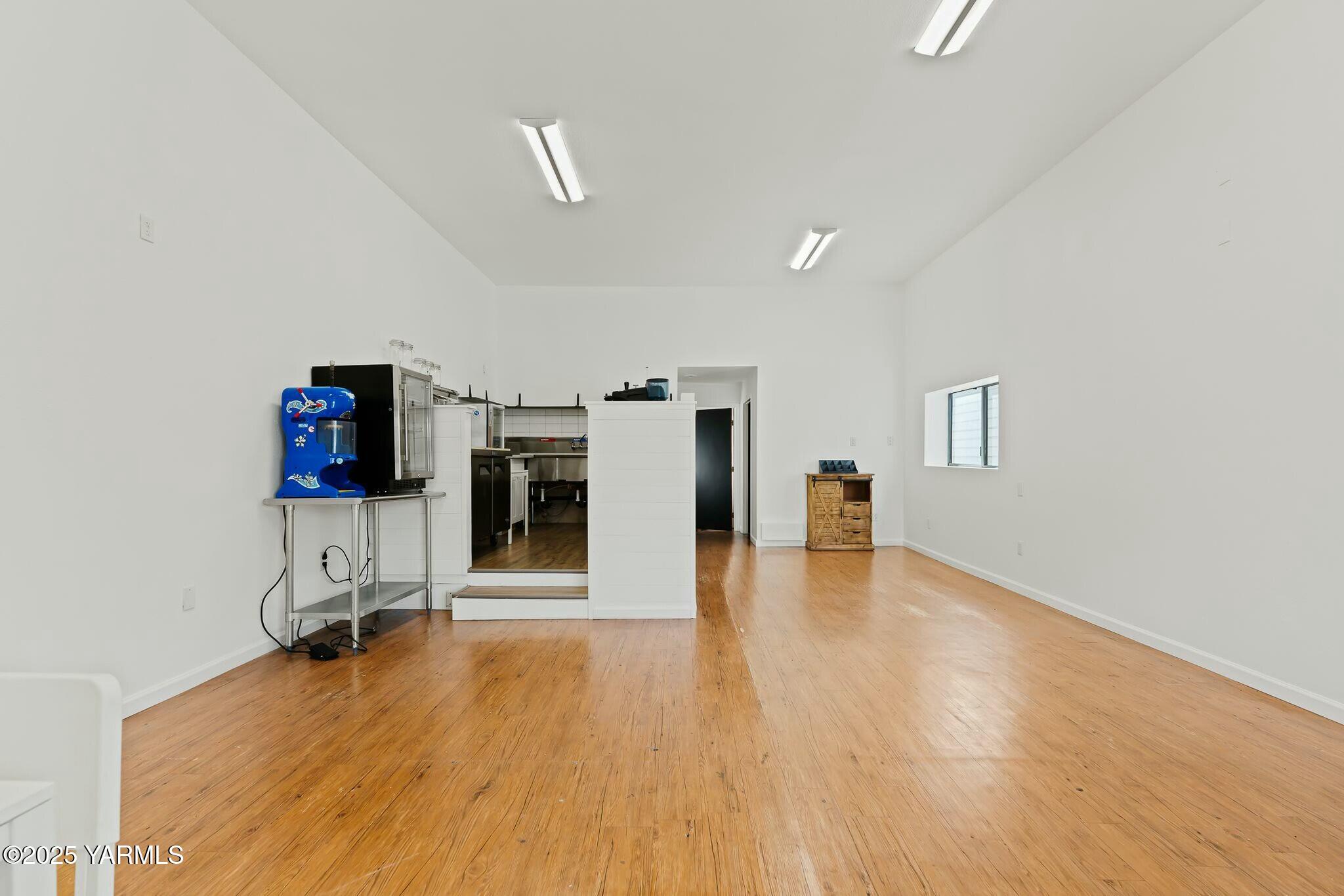 Spacious white-walled interior with wood floors and a compact service area at the back.