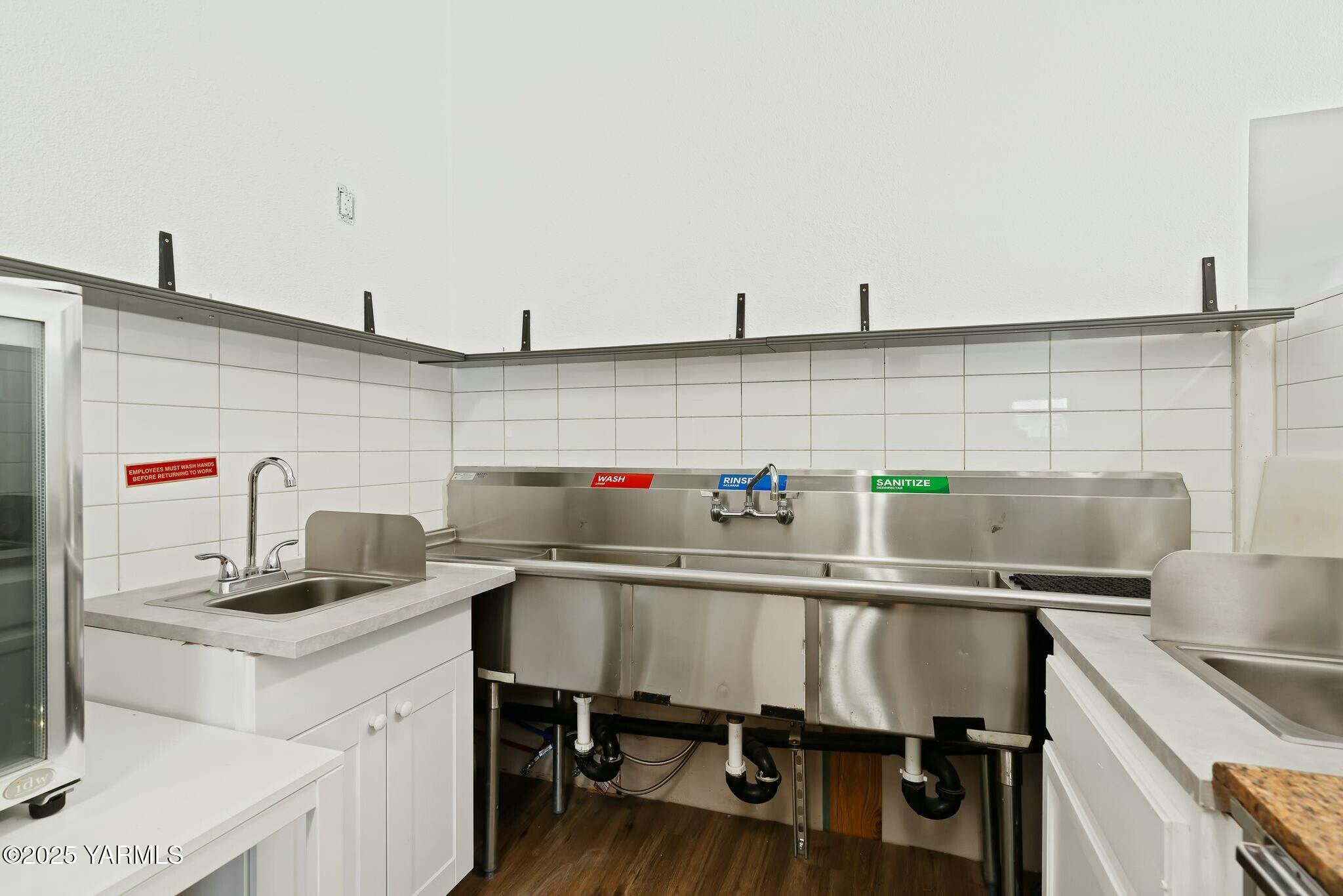 Commercial kitchen with a stainless-steel wash, rinse, and sanitize sink and a separate handwashing sink.