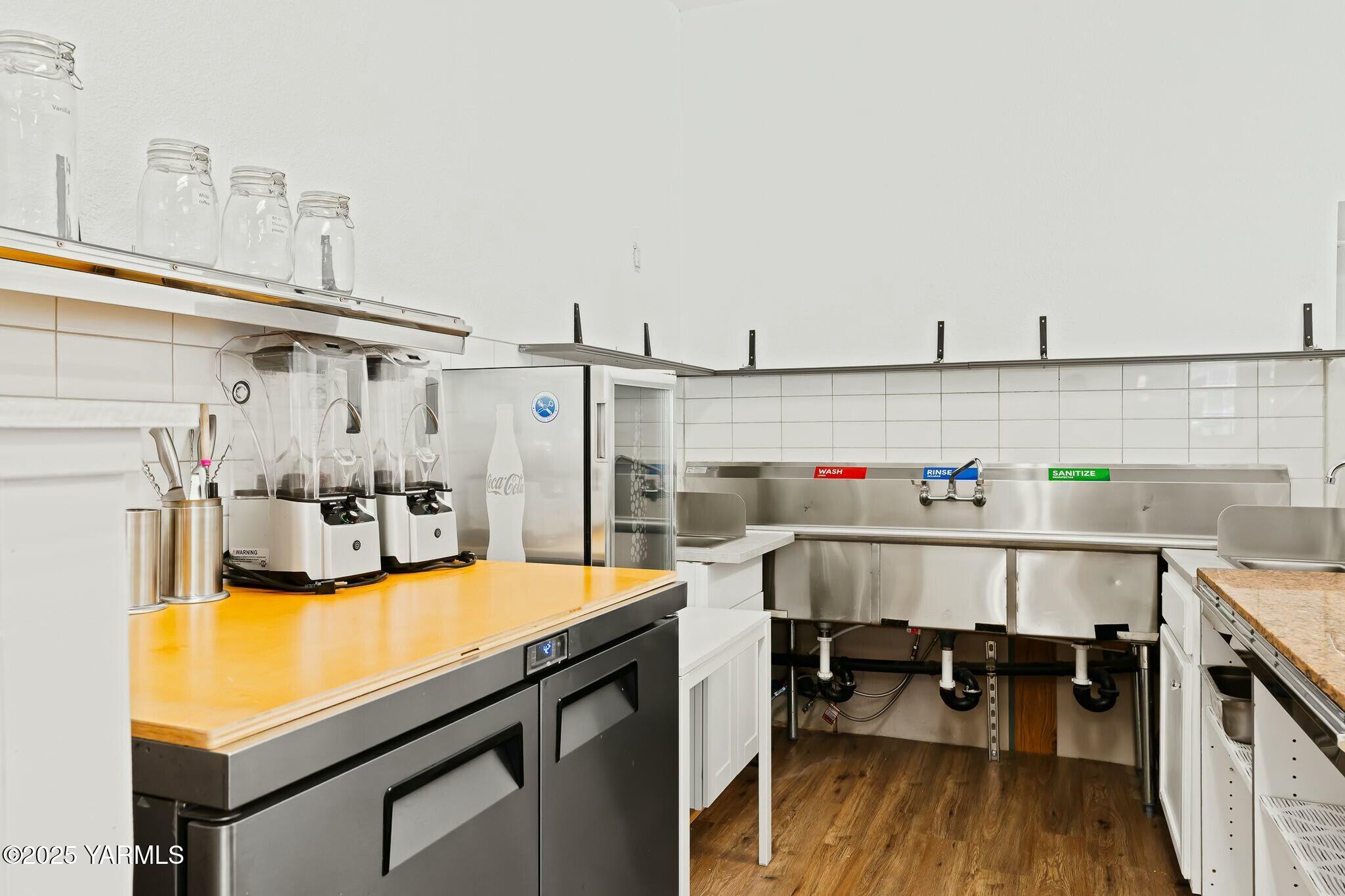 Commercial kitchen with a stainless-steel three-compartment sink and countertop equipment.