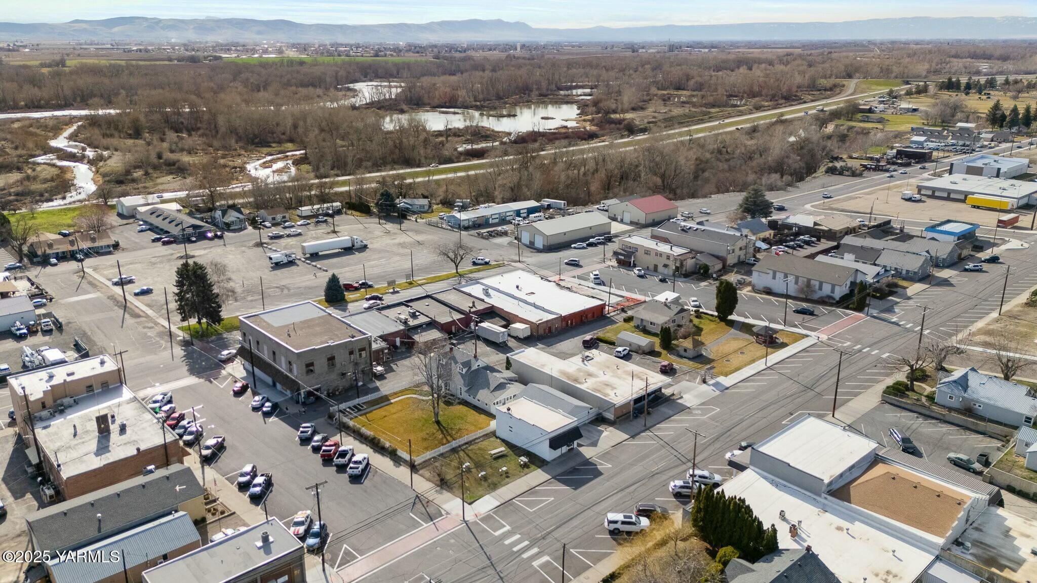 Aerial view of a commercial district beside wetlands, with mountains in the distance.