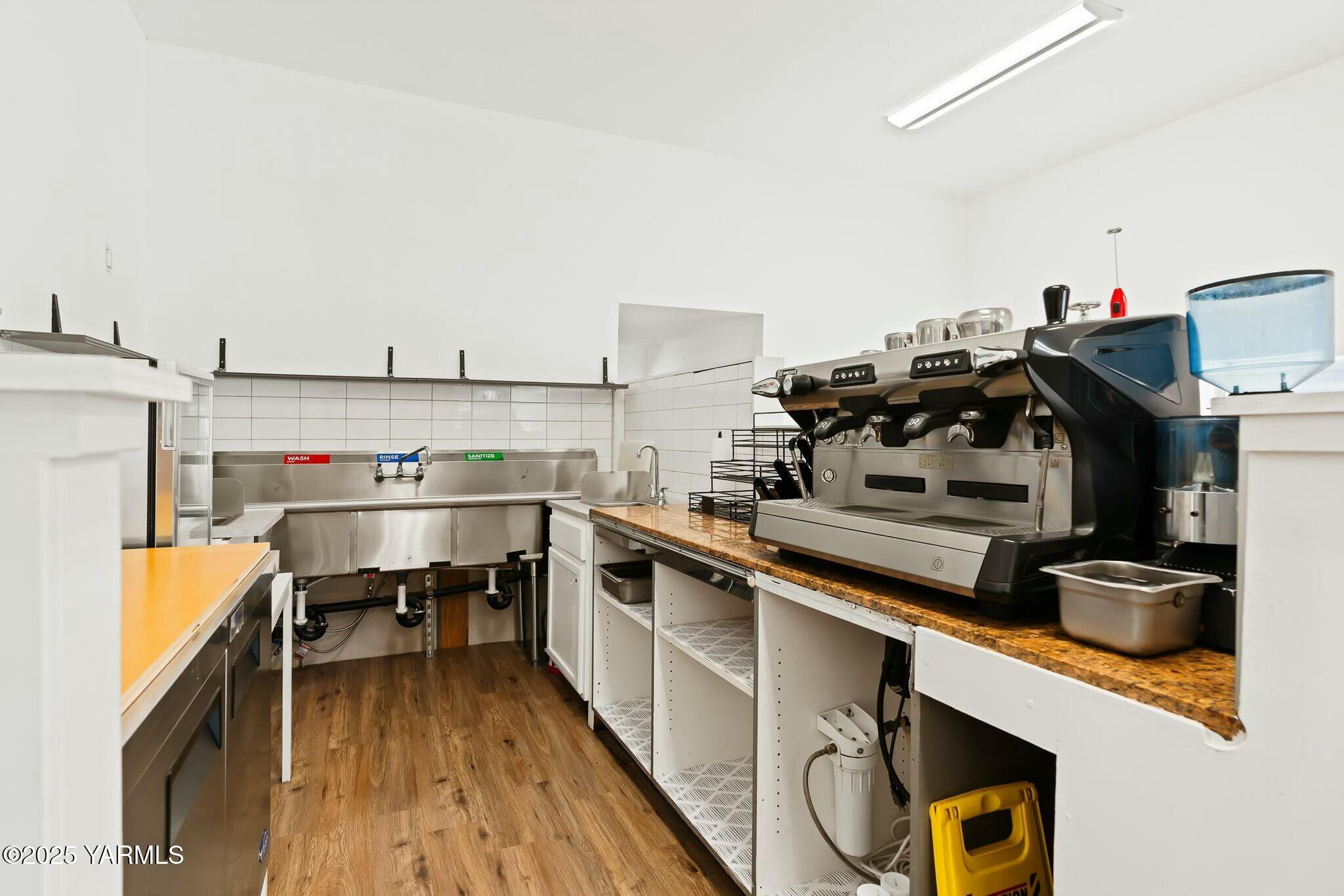 Commercial coffee prep area with a large espresso machine and stainless-steel sinks.