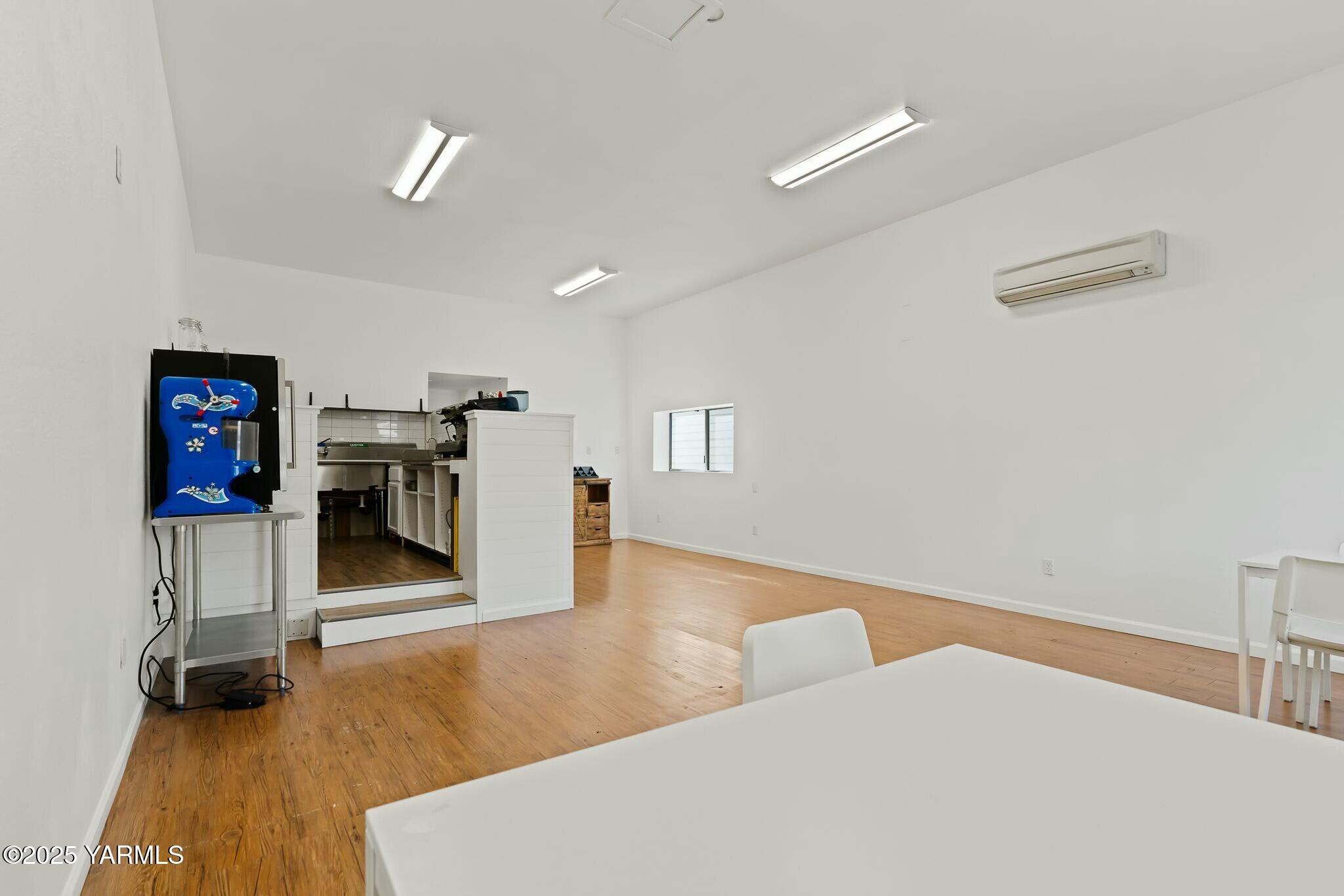 Open room with wood floors, a compact commercial kitchen, and a blue pinball machine.
