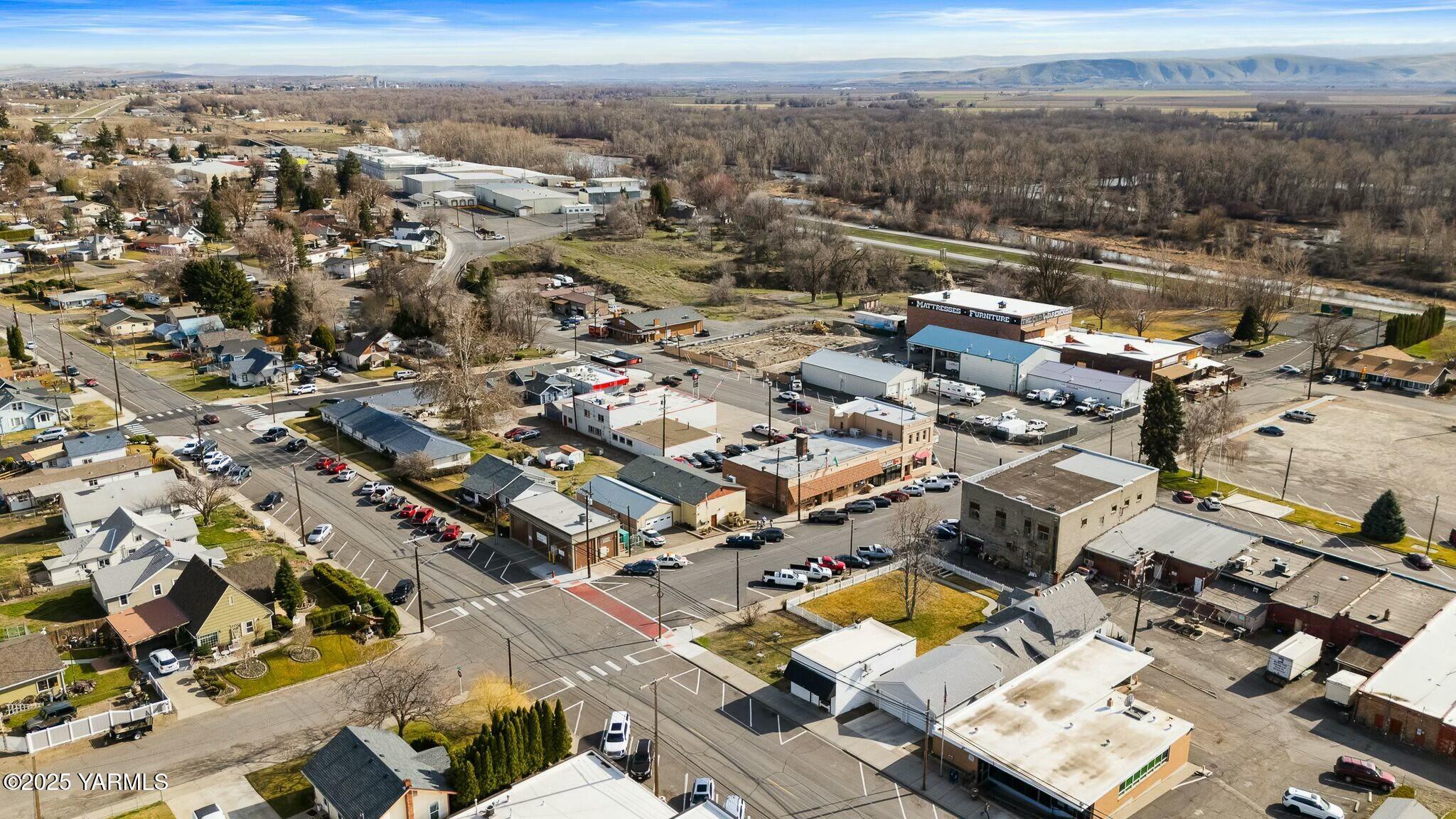 Aerial panorama of town streets and commercial buildings, with distant hills beyond.