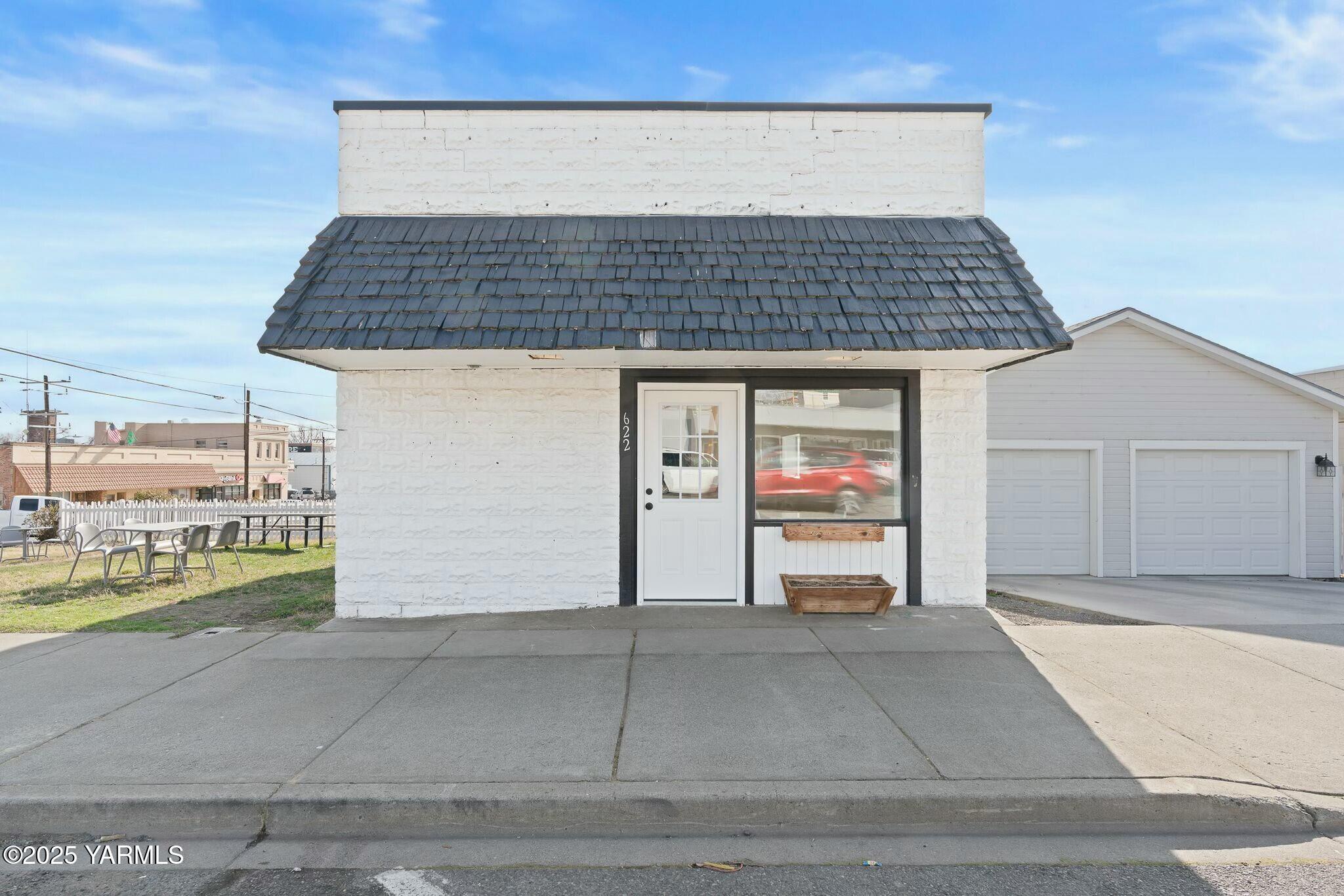 White masonry storefront with a dark tiled mansard roof and large front window.