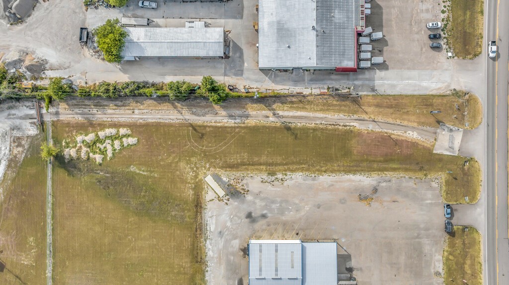 Aerial view of vacant commercial land with a paved lot beside a road.