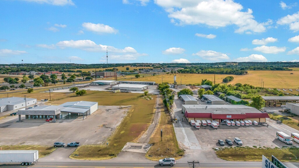 Aerial view of commercial buildings and parking areas beside open fields.