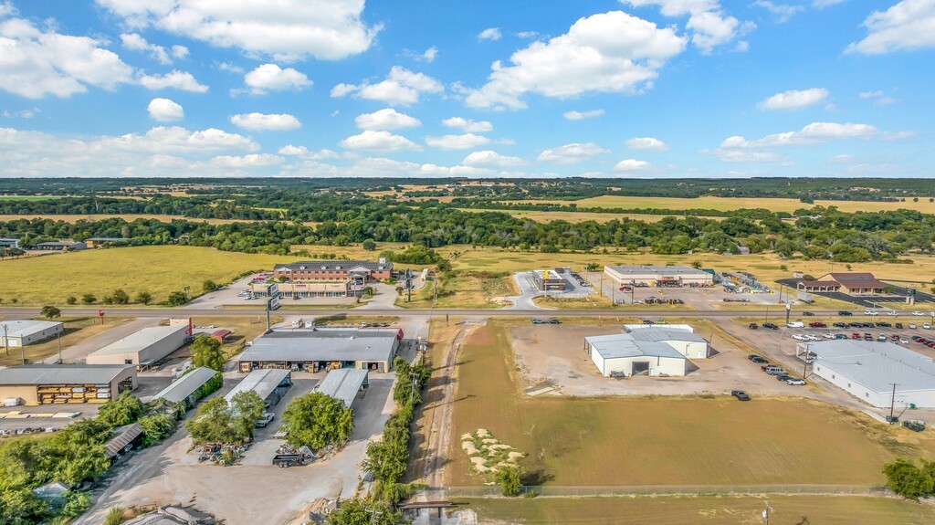 Aerial view of a cleared commercial lot beside Highway 6, surrounded by businesses and open countryside.