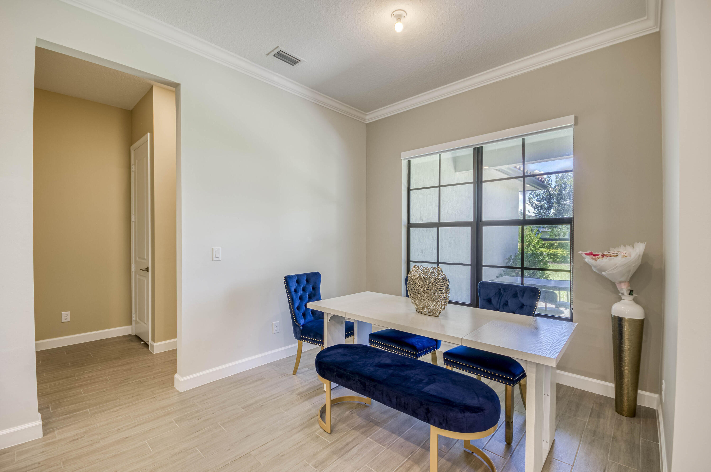 Dining area with a white table, navy seating, and a large black-grid window.
