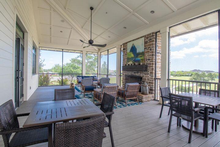 Covered patio with wicker seating, a brick fireplace, and screened views of greenery.