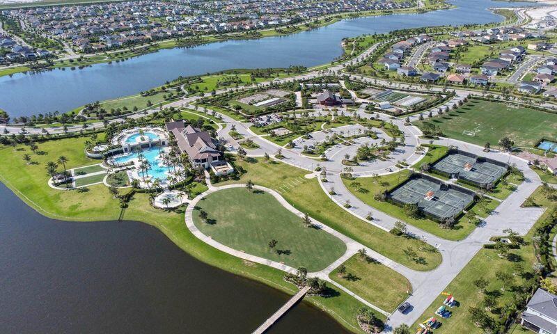 Aerial view of a lakeside community with a pool, clubhouse, and tennis courts.