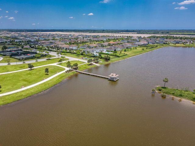 Aerial view of a lakeside community with a long dock and curving shoreline roads.