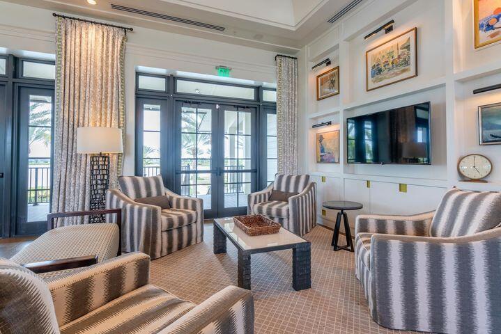 Living room with striped armchairs, a wall-mounted television, and tall glass doors.