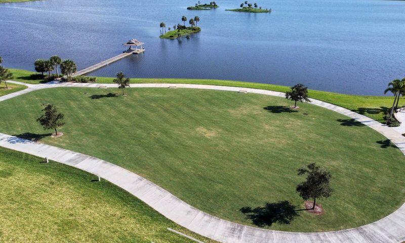 Aerial lawn beside a lake, with a curved path, long dock, and small landscaped islands.