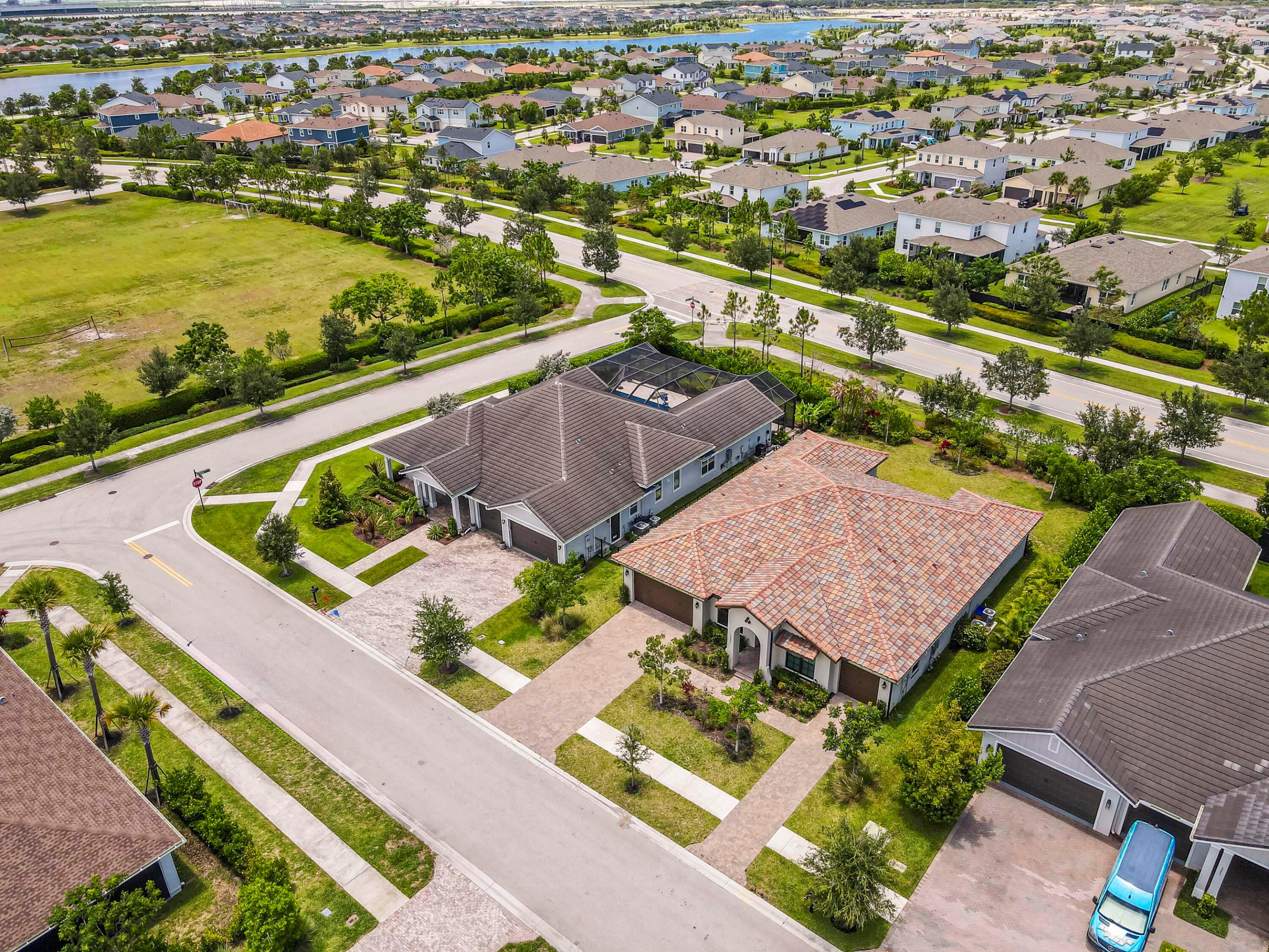 Tile-roof home with a landscaped yard, driveway, and neighboring houses, seen from above.