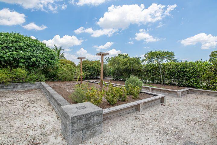 Raised garden beds with concrete borders, gravel paths, and wooden trellises.